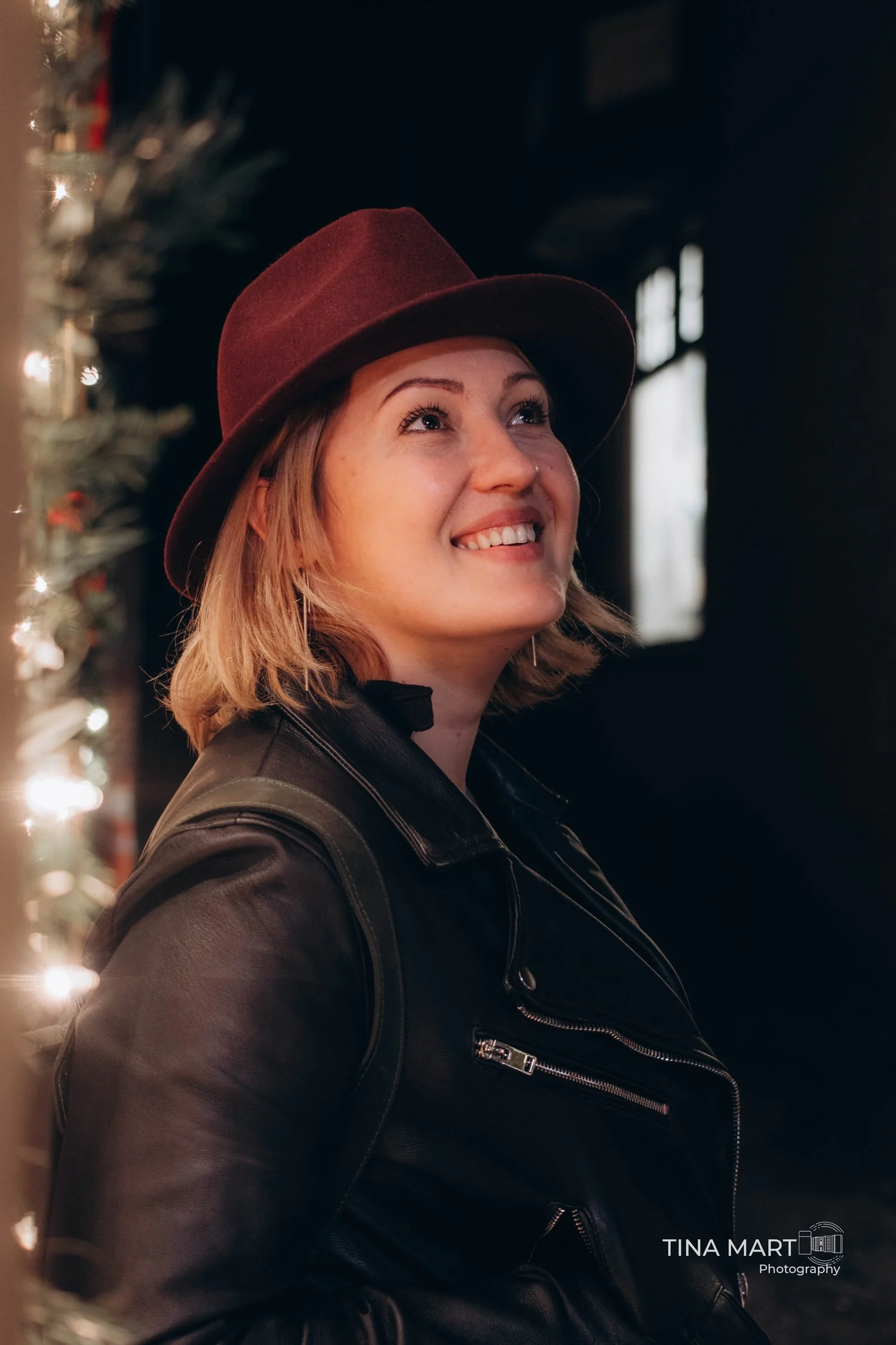 A woman in a burgundy hat looking toward the light, photographed by Tina Mart
